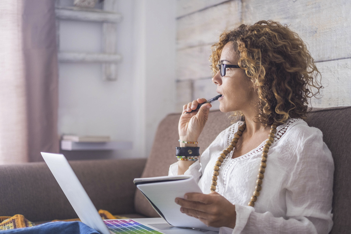 Woman sitting with a laptop wondering if she should sell her rental property in Kansas City.