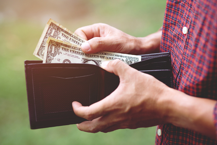 Man holding money in his wallet that he received from selling a home for cash.